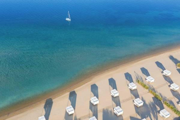 Oberflächenansicht des Ikos Olivia Hotels am Strand mit einem Boot im Wasser.