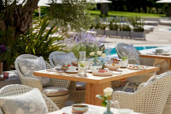 Ein Outdoor-Esstisch mit Speisen, Getränken und Blumen im Ikos Olivia Hotel.