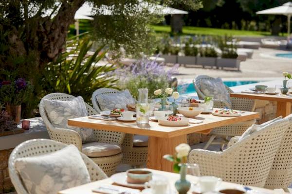 Gartensitzbereich des Ikos Olivia Hotels mit gedeckten Tischen und Stühlen.