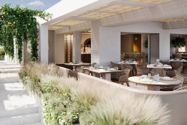 Außenbereich des Ikos Olivia Restaurants mit Tisch, Stühlen und Pflanzen.