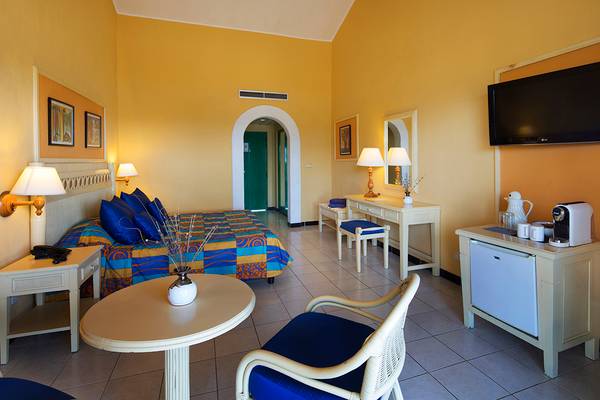 Foto eines Hotelzimmers im Memories Jibacoa Resort mit einem Bett, Tisch und Fernseher.