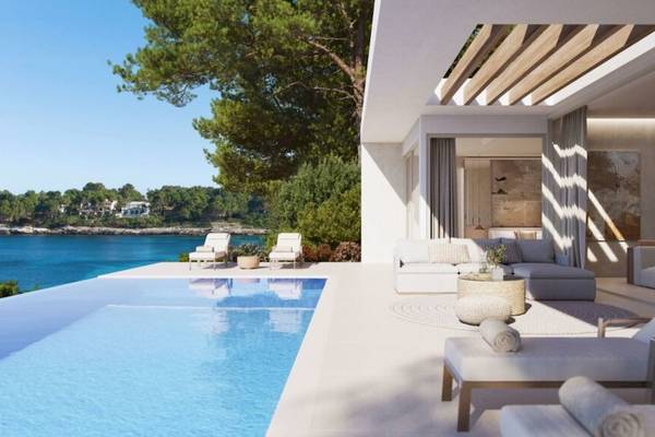 Außenbereich des Ikos Porto Petro Hotels mit Pool und Loungemöbeln am Meer.