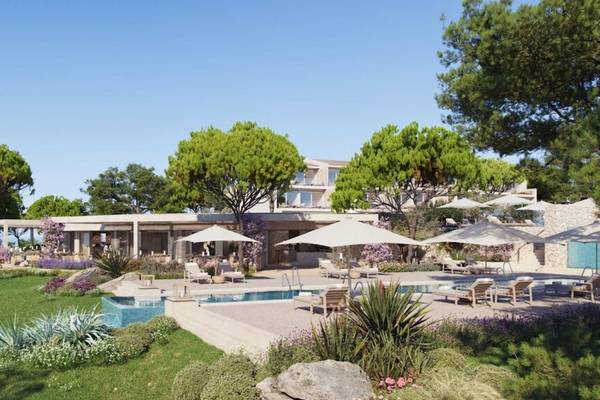 Außenbereich des Ikos Porto Petro Hotels mit Pool, Sonnenliegen und Palmen