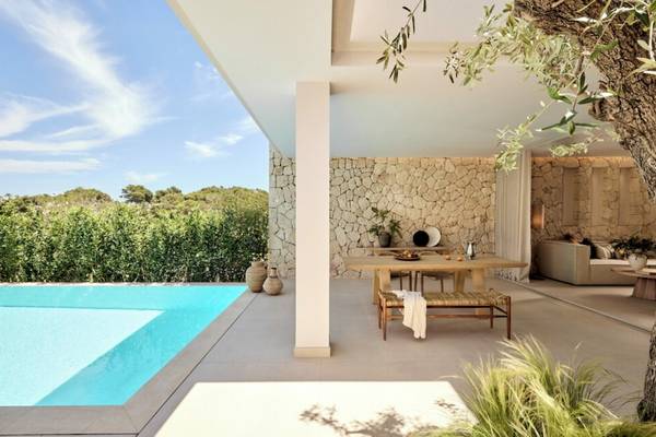 Außenbereich des Ikos Porto Petro Hotels mit Terrasse, Esstisch und Swimmingpool