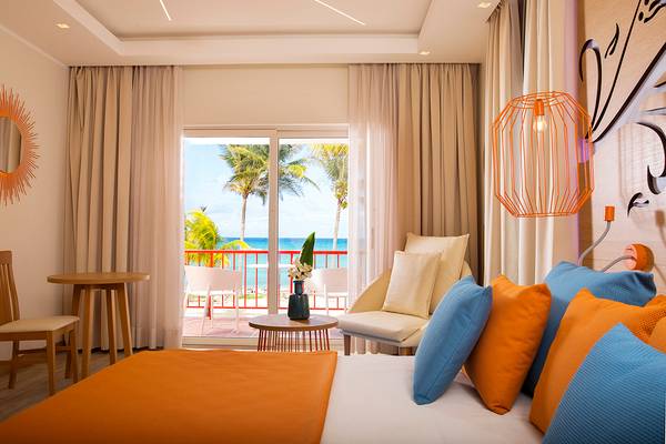 Zimmer im Memories Jibacoa Resort mit Meerblick, einem Bett, einem Tisch und einem Stuhl auf dem Balkon.