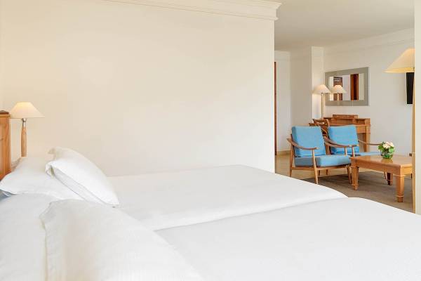 Doppelzimmer-Innenansicht im H10 Blue Mar Boutique Hotel mit zwei Betten und Wohnzimmerecke.