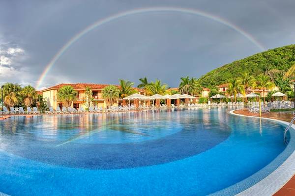 Ein großer Pool mit vielen Sonnenliegen und einem Regenbogen am Himmel, im Memories Jibacoa Resort.