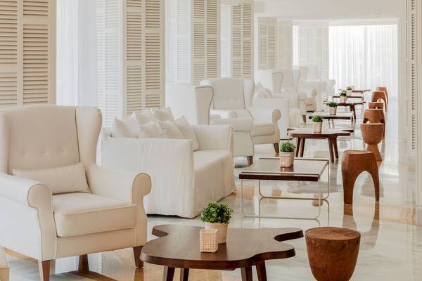 Loungebereich des H10 Blue Mar Boutique Hotels mit weißen Sesseln und Tischen.