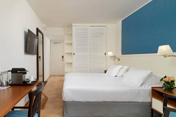 Doppelzimmer im H10 Blue Mar Boutique Hotel mit zwei Betten, Schreibtisch und Fernseher.