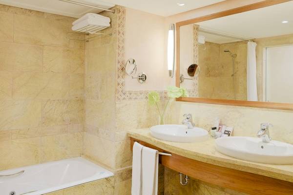 Badezimmer im H10 Blue Mar Boutique Hotel mit Badewanne, Spiegel und zwei Waschbecken.