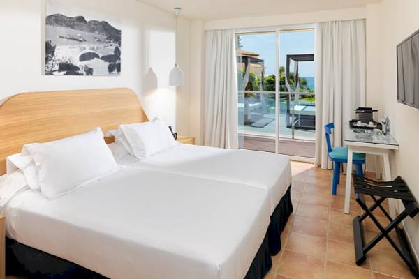 Doppelbettzimmer im H10 Blue Mar Boutique Hotel mit Blick auf den Pool.
