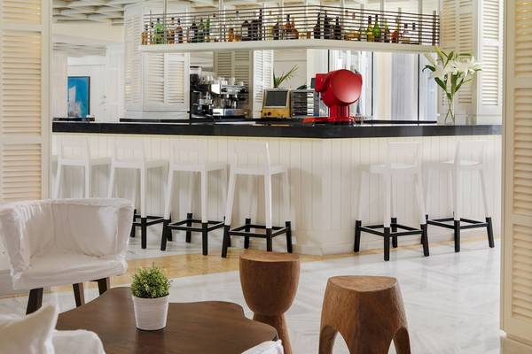 Barbereich im H10 Blue Mar Boutique Hotel mit weißen Stühlen und schwarzem Tresen.