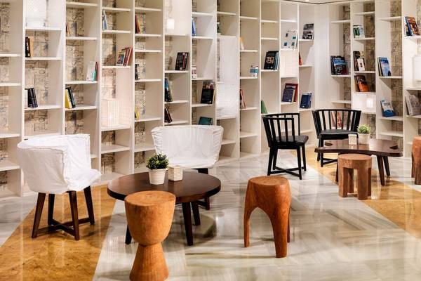 Lobby des H10 Blue Mar Boutique Hotels mit Bücherregalen, Stühlen und Tischen.
