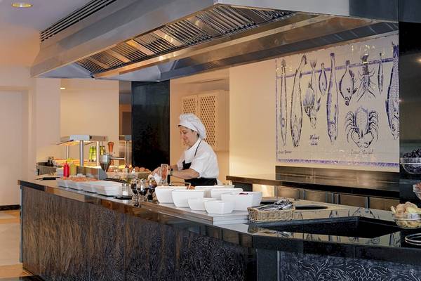 Buffet-Counter im H10 Blue Mar Boutique Hotel mit Köchin, die Salat serviert.