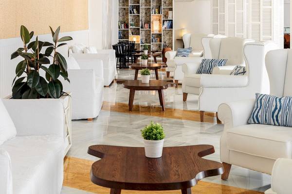Lobby des H10 Blue Mar Boutique Hotels mit weißen Möbeln, Tischen und Pflanzen.