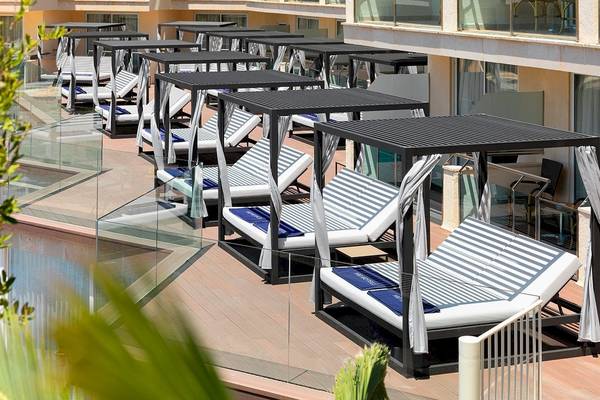 Loungebereich des H10 Blue Mar Boutique Hotels mit vielen Liegebetten und Blick auf den Pool.