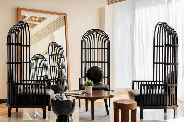Loungebereich im H10 Blue Mar Boutique Hotel mit schwarzen Vogelkäfig-Stühlen und einem Tisch.