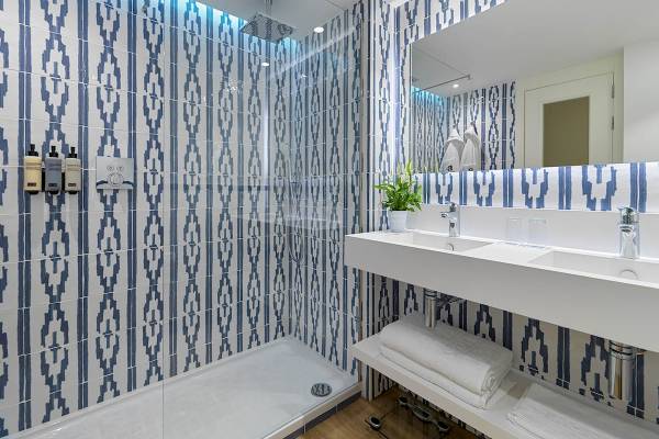 Badezimmer des H10 Blue Mar Boutique Hotels mit blau-weißen gemusterten Fliesen und einem Duschbereich.