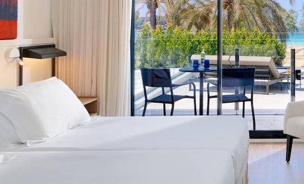 Zimmer im H10 Casa del Mar Hotel mit Blick auf den Balkon, zwei Betten und weißen Möbeln.