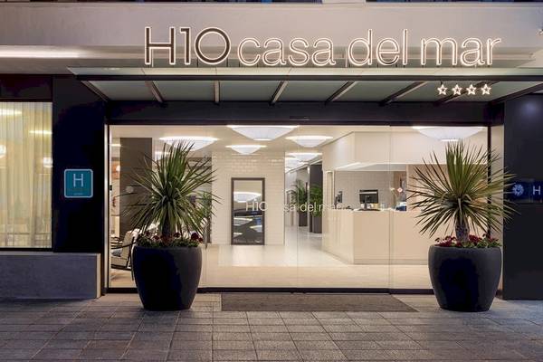 Eingang des H10 Casa del Mar Hotels mit Logo und zwei großen Topfpflanzen vor dem Gebäude.