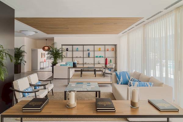 Wohnzimmer im H10 Casa del Mar Hotel mit weißen Möbeln, Büchern und Kerzen.