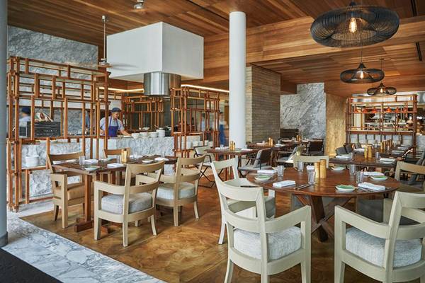 Innenansicht des Restaurants im FIVE Palm Jumeirah mit Holztischen, Stühlen und Holzelementen.