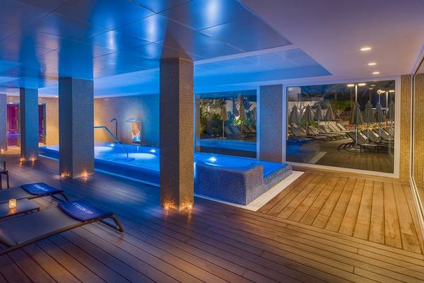 Beleuchteter Innenpool des H10 Casa del Mar Hotels bei Nacht mit Lounge-Liegestühlen und blauer Beleuchtung.