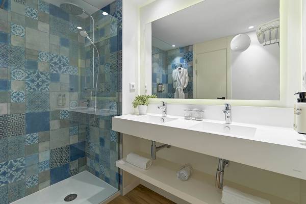 Badezimmer des H10 Casa del Mar mit blauen gemusterten Fliesen und einer großen Dusche.