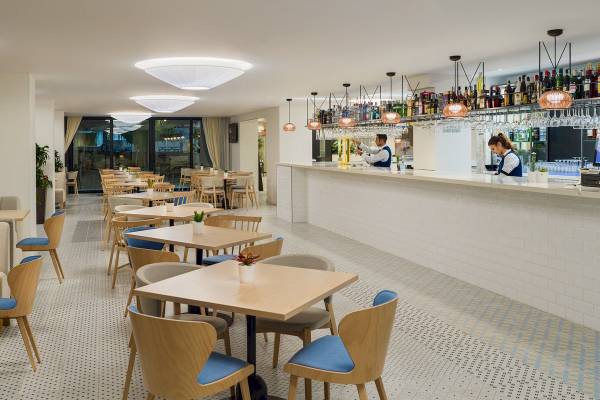 Innenbereich des H10 Casa del Mar Hotels mit Bar und Tischen, wo Angestellte hinter der Theke stehen.