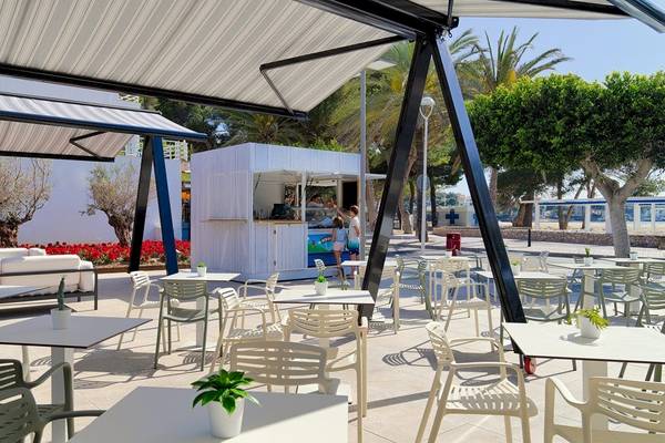 Außenbereich des H10 Casa del Mar Hotels mit Tischen, Stühlen und Pavillons.