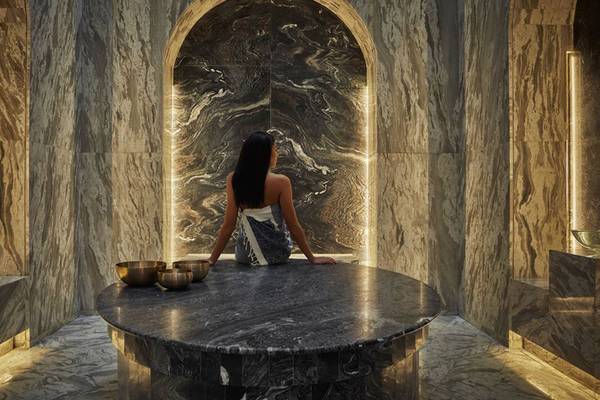 Eine Frau im Spa-Bereich des FIVE Palm Jumeirah mit Blick auf eine Marmorwand.