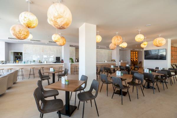 Innenansicht des Restaurants im Nautic Hotel & Spa mit runden Lampen und runden Tischen.