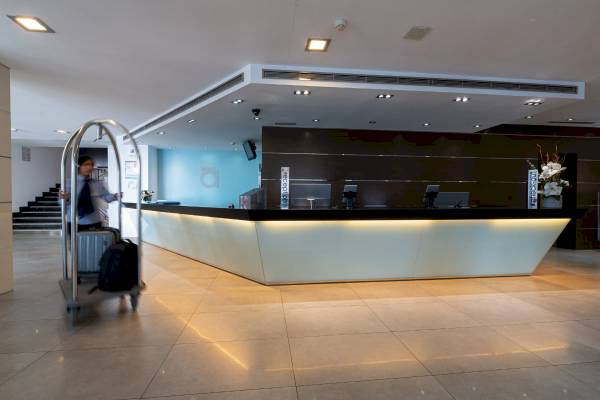 Empfangsbereich des Nautic Hotel & Spa mit einem Mitarbeiter, der einen Gepäckwagen schiebt