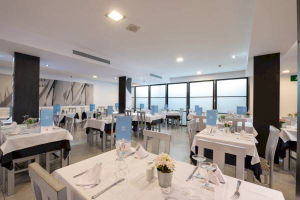 Innenbereich des Restaurants im Nautic Hotel & Spa mit gedeckten Tischen und Blumenarrangements.