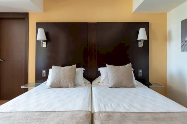 Doppelbett im Hotelzimmer im Nautic Hotel & Spa mit weißen Laken und Kissen.