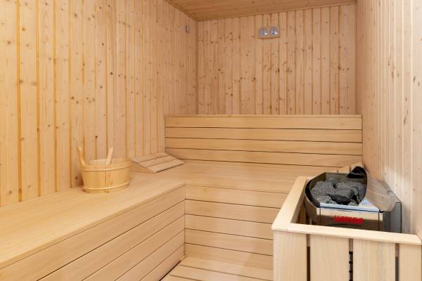 Innenansicht einer Sauna im Nautic Hotel & Spa mit Holzwänden, Bänken, Thermometer und einem Harvia Ofen.