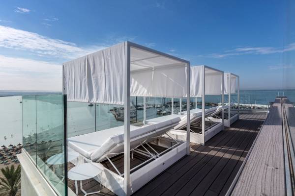 Terrasse des Nautic Hotel & Spa mit weißen Loungebetten und Glaswänden, Blick aufs Meer