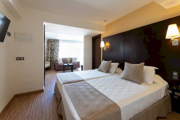 Doppelbettzimmer im Nautic Hotel & Spa mit Blick auf ein Wohnzimmer.