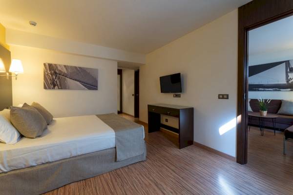Foto eines geschmackvoll eingerichteten Zimmers im Nautic Hotel & Spa mit Doppelbett, Fernseher und einem kleinen Schreibtisch.