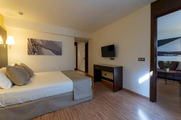 Schlafzimmer im Nautic Hotel & Spa mit Doppelbett, Fernseher und Wohnzimmerbereich.