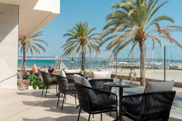 Terrasse des Nautic Hotel & Spa mit Blick auf den Strand und Palmen.