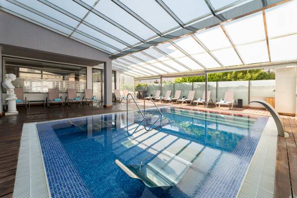 Ein Swimmingpool unter einem Glasdach mit Liegestühlen und einer Statue