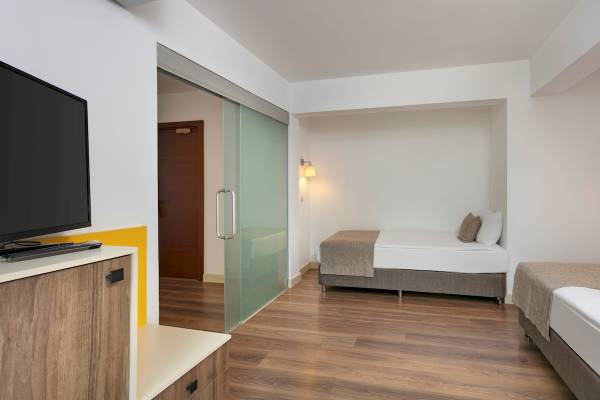 Innenansicht eines Zimmers im Monachus Family Resort Sorgun mit zwei Betten und Fernseher.