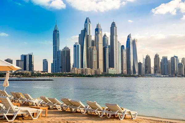 Foto von der Küste des Five Palm Jumeirah mit vielen Liegestühlen und einer Stadtlandschaft im Hintergrund.