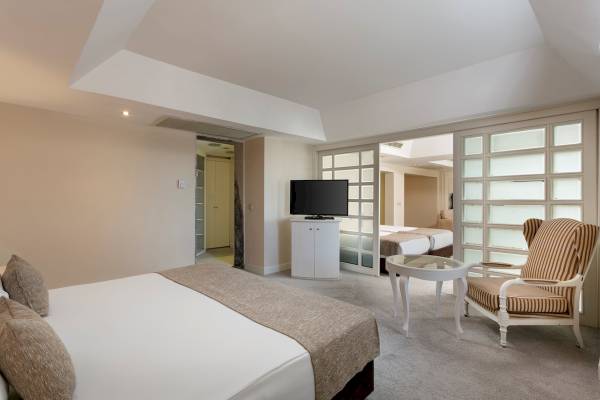 Schlafzimmer im Monachus Family Resort Sorgun mit Doppelbett, Fernseher, Beistelltisch und Sessel.