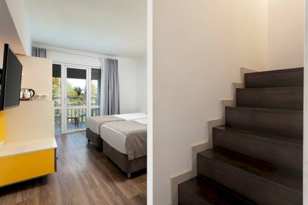Innenansicht eines Hotelzimmers im Monachus Family Resort Sorgun mit zwei Betten und einem Balkon.