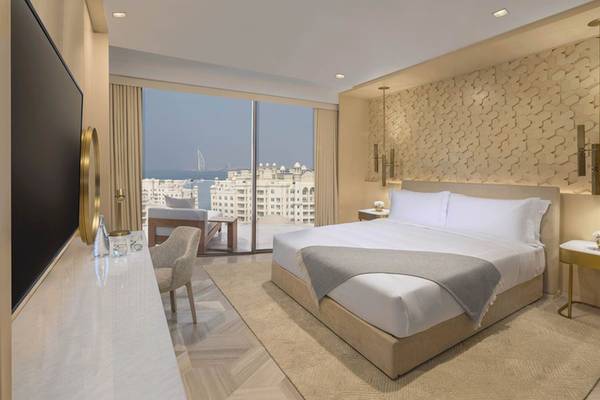 Innenansicht eines Schlafzimmers im FIVE Palm Jumeirah Hotel mit Bett, Fernseher und Ausblick auf die Stadt.