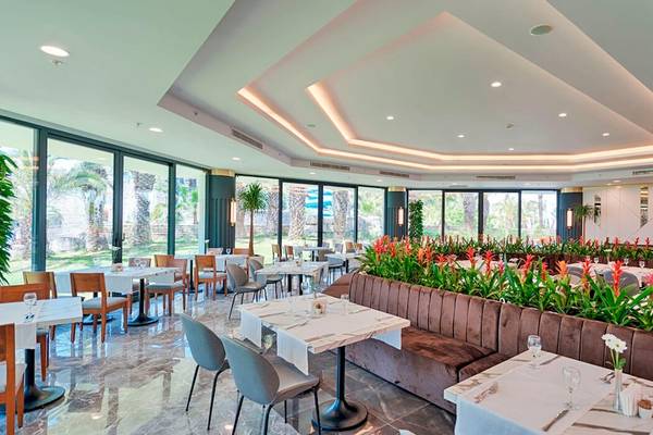 Restaurantbereich im Monachus Family Resort Sorgun mit braunen Bänken und Tischdekoration.