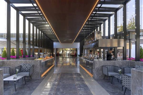 Innenbereich des Monachus Family Resort Sorgun mit Marmorboden, Sitzgelegenheiten und Buffetbereich.