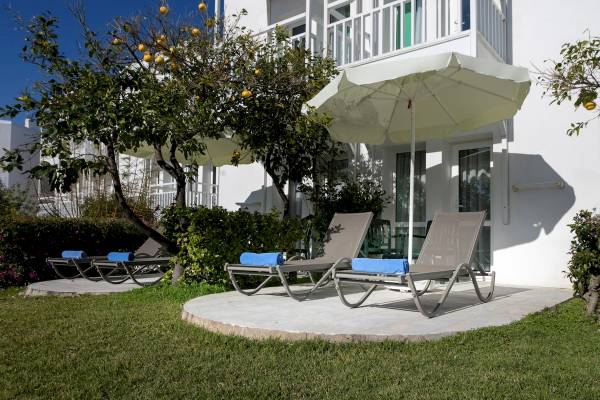 Loungebereich des Monachus Family Resort Sorgun mit Sonnenliegen und Schirmen im Freien.